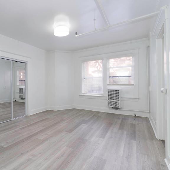 an empty living room with white walls and a mirrored closet at clay & tiffany, portland, or