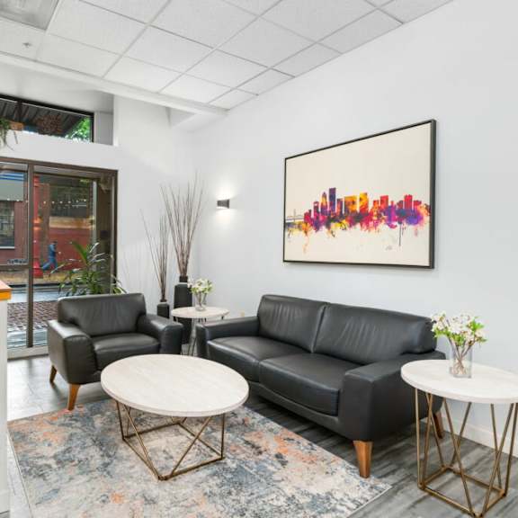 a black leather couch sits in a room with a large picture frame on the wall.at fifth avenue place apartments, portland