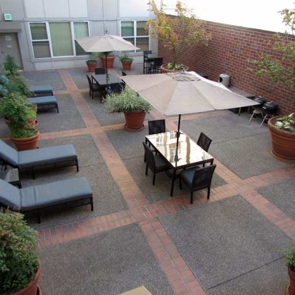 a patio with tables and chairs and umbrellas.at fifth avenue place apartments, oregon, 97209