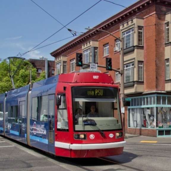 a red and blue train is on a track in front of a building at midtown apartments, oregon, 97209