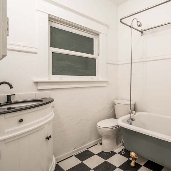 a white bathroom with a black and white checkered floor at midtown apartments, oregon, 97209