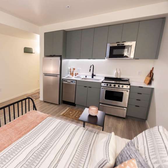a bedroom with a bed and a kitchen with stainless steel appliances at moraine, tacoma, wa