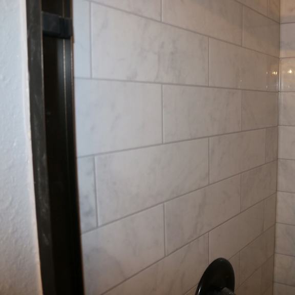 a tiled shower in a bathroom with a person standing in it at schaefer ridge apartments, branson , mo 65616