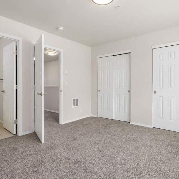 a bedroom with two doors and a bathroom in the background