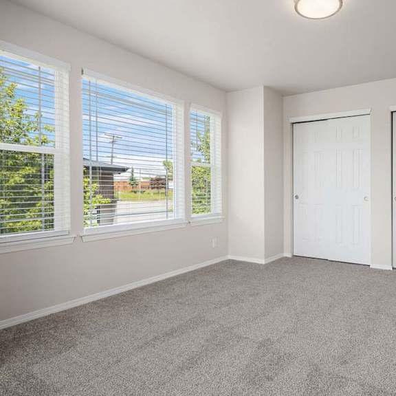 a bedroom with three windows and a door