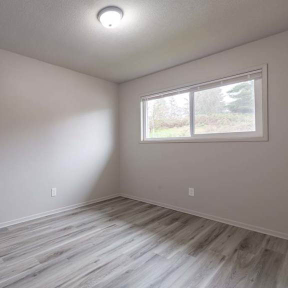 an empty room with a window and a wooden floor