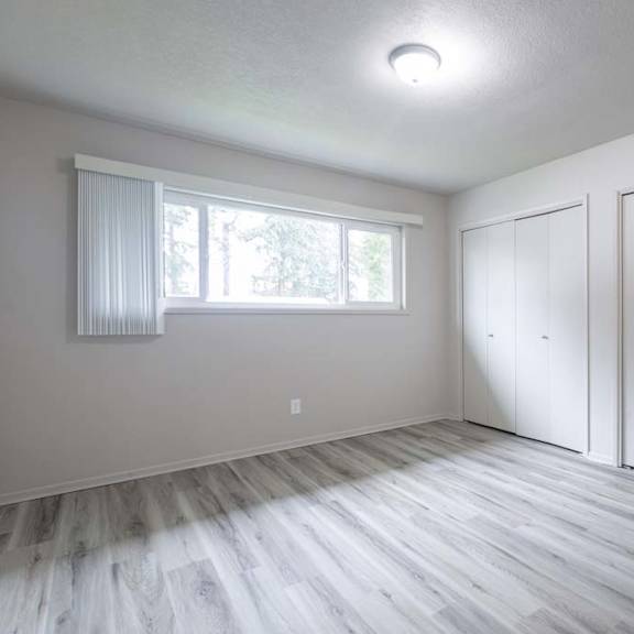 an empty bedroom with a large window and white closets