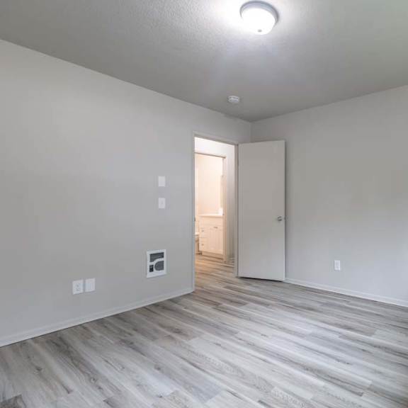 a bedroom with hardwood floors and white walls