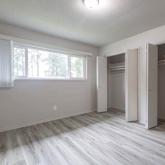 an empty bedroom with a large window and a closet