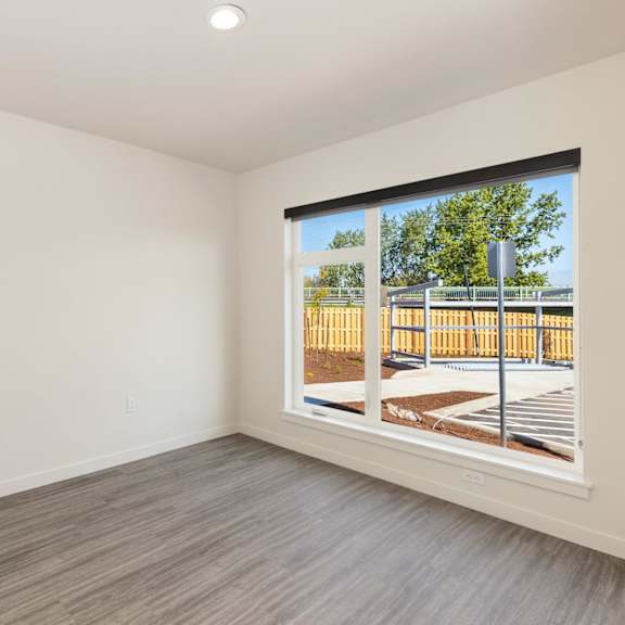 a bedroom with two large windows and a wooden fence