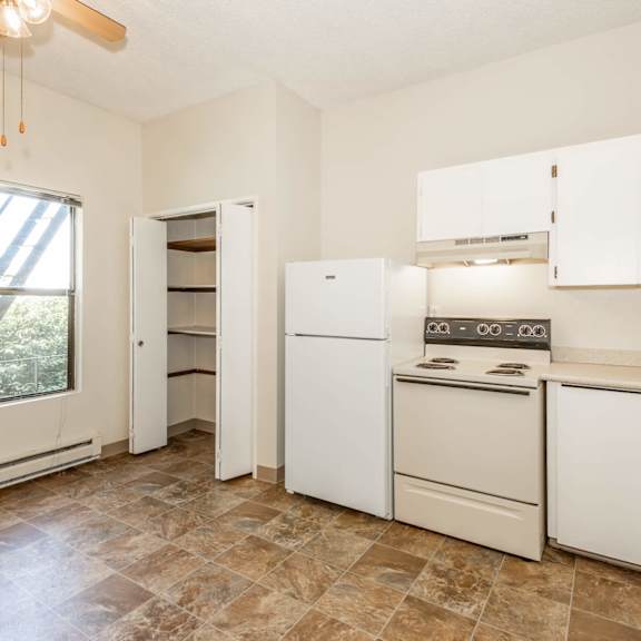 a kitchen with white appliances and brown tiled floors.
