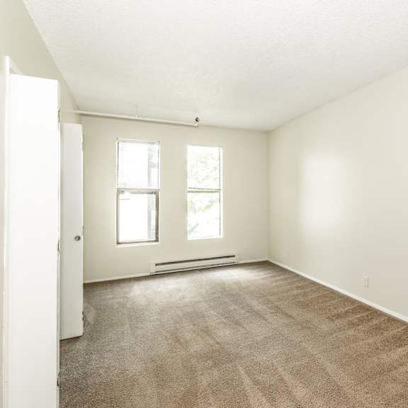 a room with a carpeted floor and two windows.