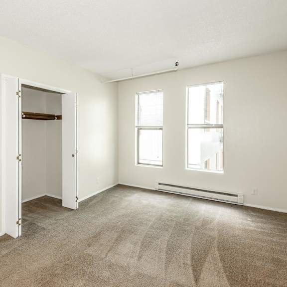a room with a carpeted floor, two windows, and a door.