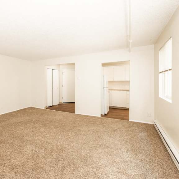 a large, empty room with carpeted flooring and white walls.