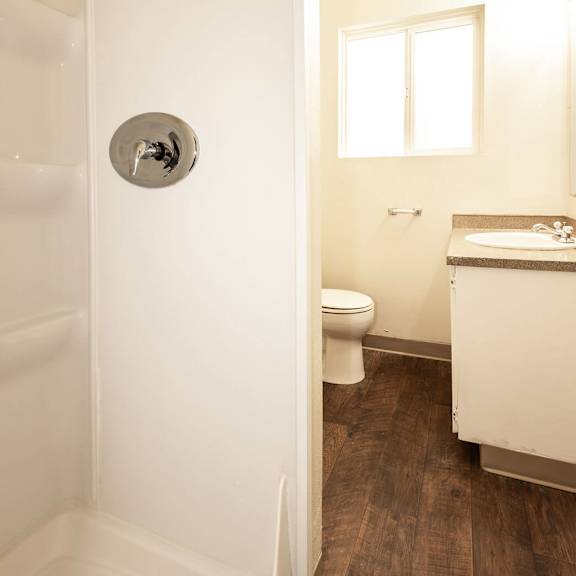 a white bathroom with a toilet, sink, and shower.