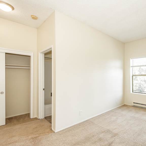 a room with a carpeted floor, a window, and a door.