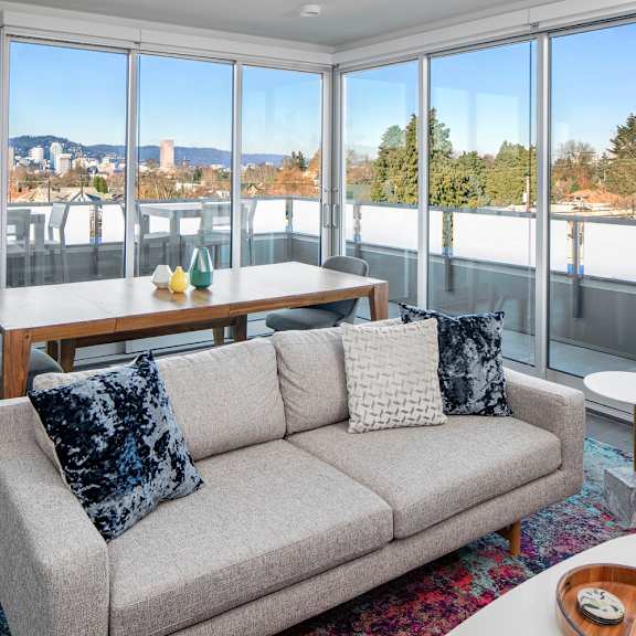 a living room with a grey couch and a table with a vase of flowers on it.