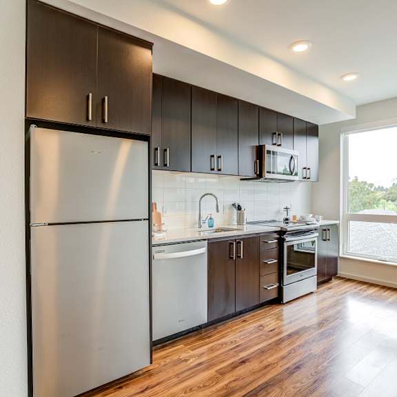 a modern kitchen with dark wood cabinets and stainless steel appliances.