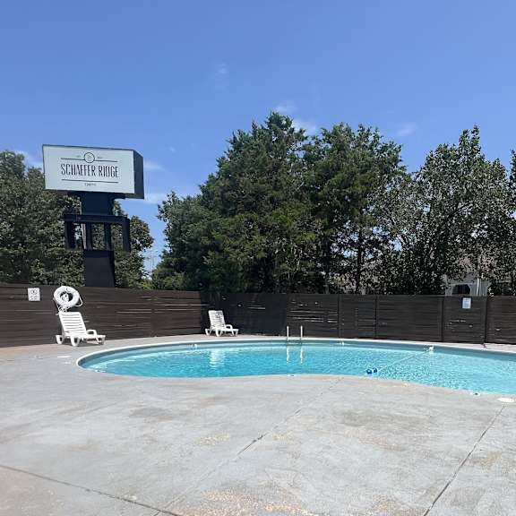 a swimming pool at a hotel with a fence and trees at schaefer ridge apartments, missouri