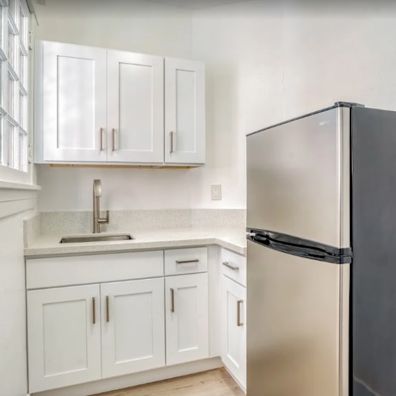 a black refrigerator sits next to a sink in a kitchen with white cabinets at clay & tiffany, portland, 97201