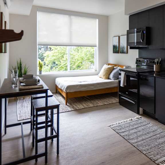 a kitchen and living room with a large window and black cabinets at shift, portland, or 97217