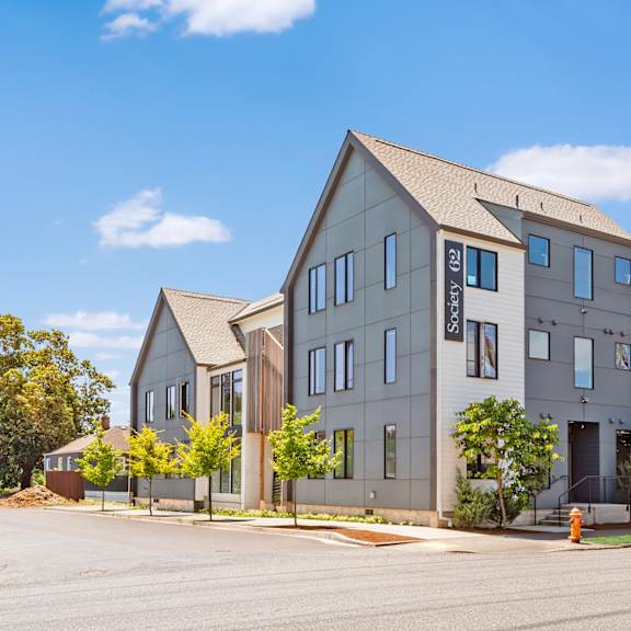 a modern two-story building with a flat roof and a large front yard at society 62 apartments, portland 97213