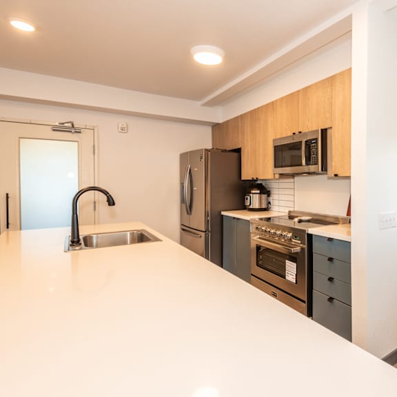 a modern kitchen with wooden cabinets and stainless steel appliances at society 62 apartments, oregon