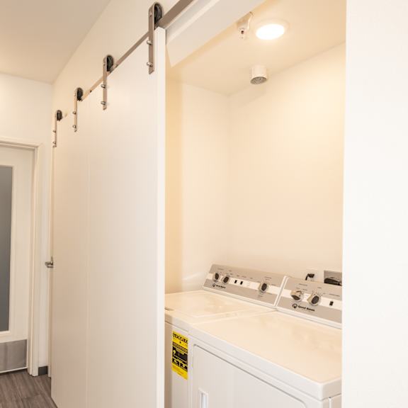 a white washing machine is in a small laundry room at society 62 apartments, oregon, 97213