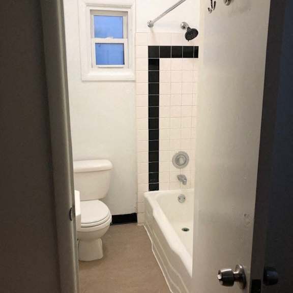a bathroom with a toilet and a tub and a window