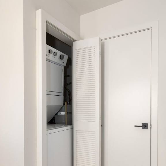 a white door is open to a kitchen with a white oven.