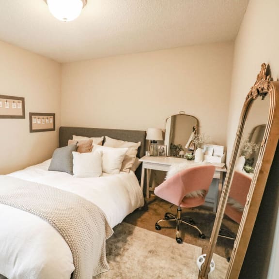 a bedroom with a bed and a vanity with a mirror