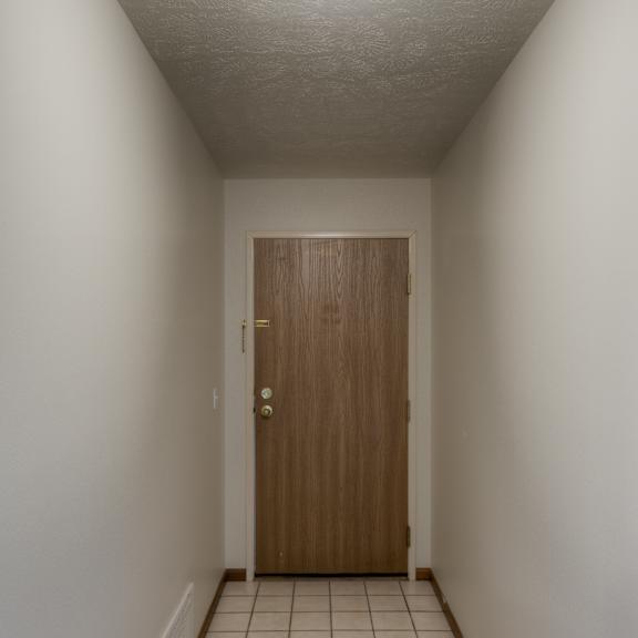 a hallway with a brown door and tiled floor.