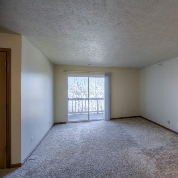 a room with a carpeted floor and a sliding glass door leading to a balcony.