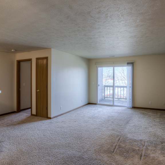 a room with a carpeted floor and a window with blinds.