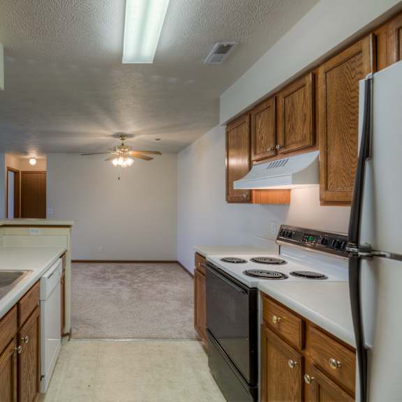 a kitchen with a white refrigerator, a stove, a sink, and wooden cabinets.