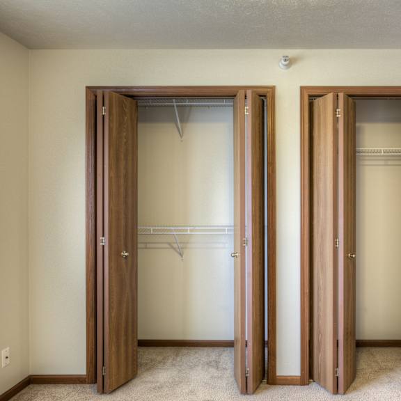 three wooden closet doors are open in a room.