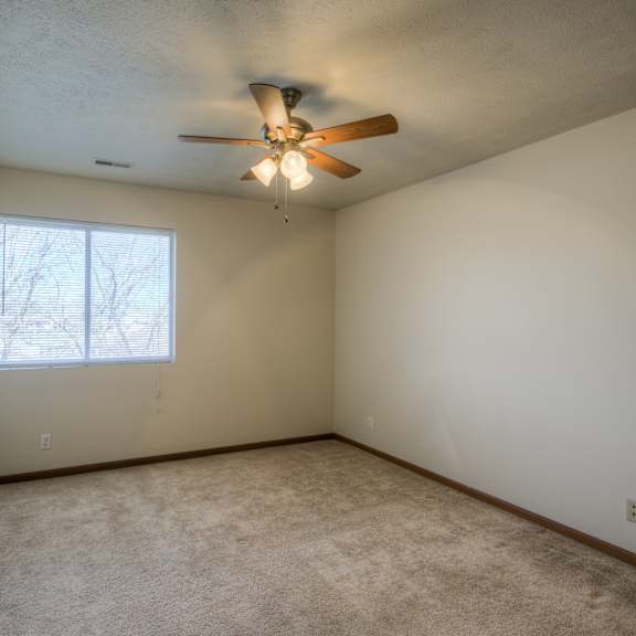 a room with a ceiling fan and a window.
