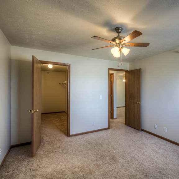 a room with a ceiling fan and carpeted floor.