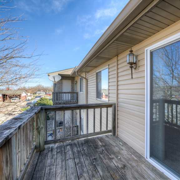 a deck with a sliding glass door leading to a backyard.
