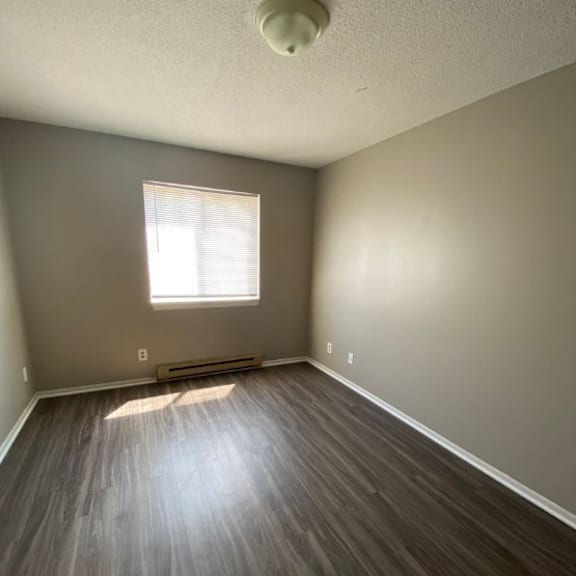 a room with a window and wooden flooring.