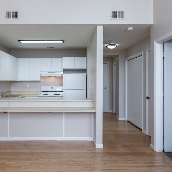 a kitchen with white cabinets and a wooden floor.