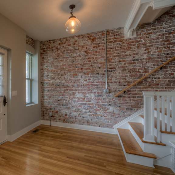 a room with a wooden floor and a brick wall.