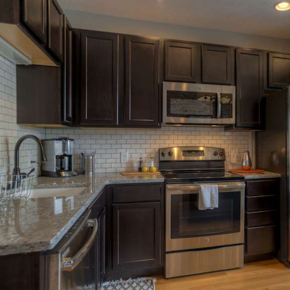 a modern kitchen with dark brown cabinets and stainless steel appliances.