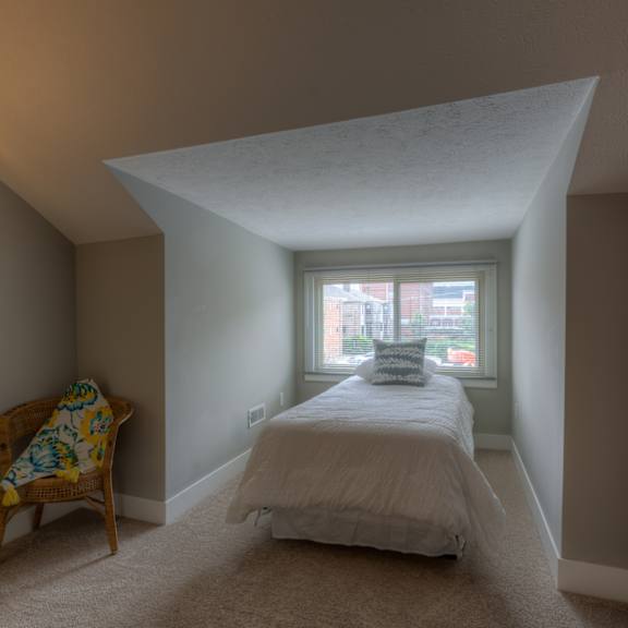 a bedroom with a bed, chair, and window.