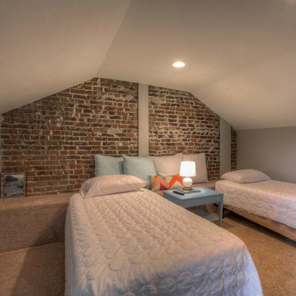 two twin beds in a room with a brick wall.