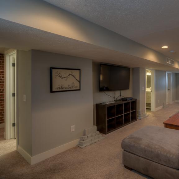 a living room with a grey couch and a television on the wall.