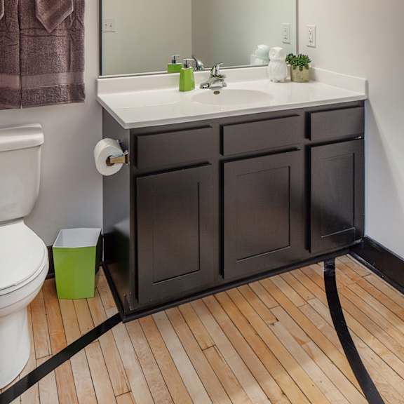 a bathroom with a white sink and a brown cabinet.