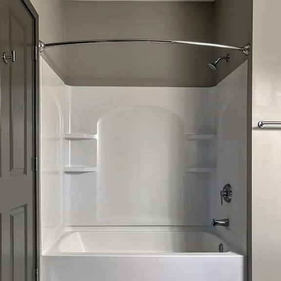 a white bathtub in a bathroom with a grey door.