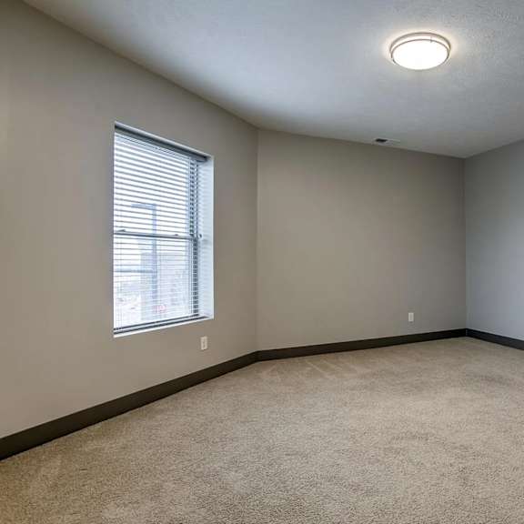a room with a carpeted floor and a window with blinds.
