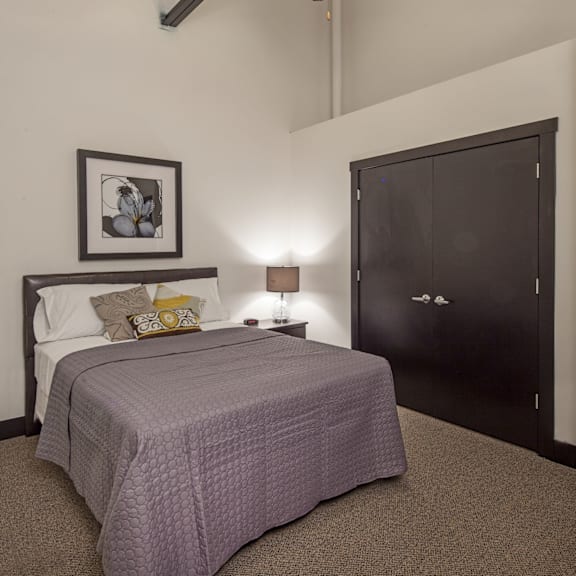 a bedroom with a bed, a ceiling fan, and a painting on the wall.